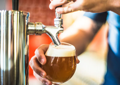 Close-up of man pouring beer in bar