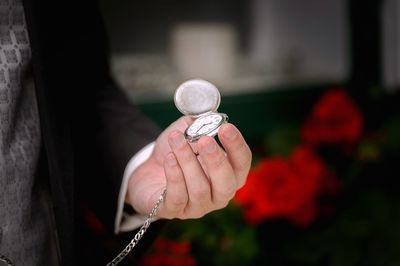 Midsection of person holding pocket watch at home