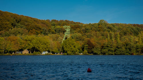 Scenic view of lake by trees against blue sky