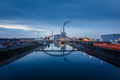 Illuminated bridge over river against sky in city