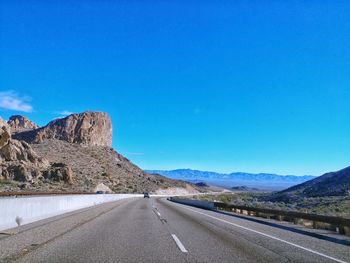 Road by mountains against clear blue sky