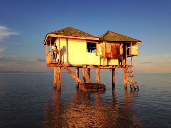 Traditional house by sea against sky