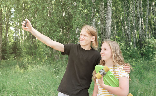 Woman smiling while standing by trees against plants