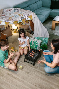 Top view of family grilling and eating sausages on barbecue while camping at home