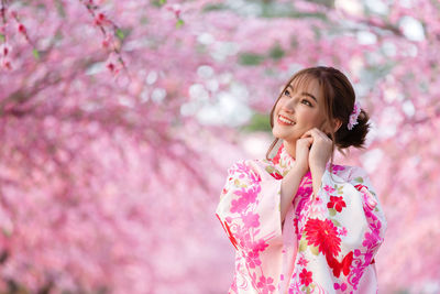 Woman standing on pink cherry blossom tree