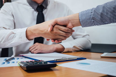 Midsection of businessman shaking hands with colleague