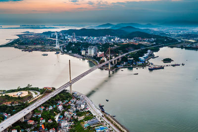 Aerial view of bridge over bay in city during sunset