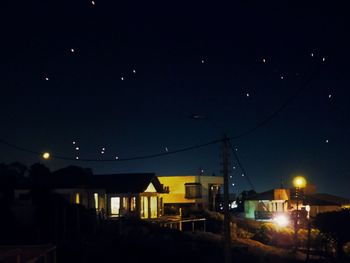 Illuminated houses against sky at night