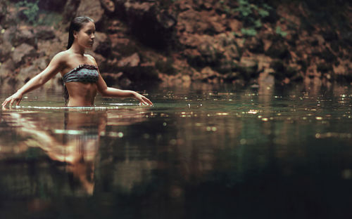 Full length of shirtless woman in lake