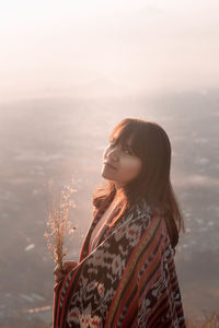 Woman looking at camera against sky during sunset