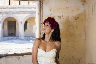 Beautiful young woman standing against wall