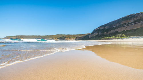 Scenic view of beach against clear blue sky