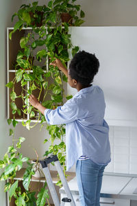 Side view of young woman standing against wall