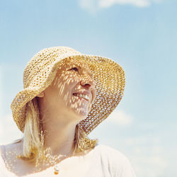 Low angle view of smiling woman wearing hat against sky