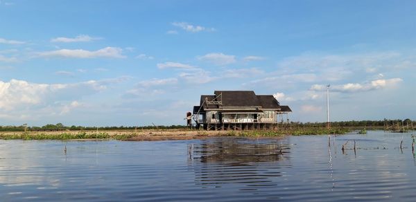 House on lake by building against sky