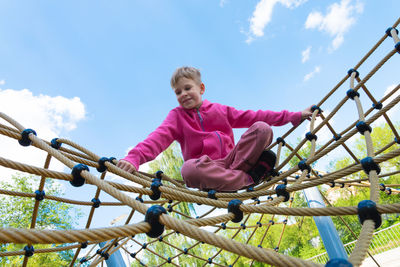 Low angle view of girl playing in playground against sky