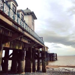 View of pier on beach against cloudy sky