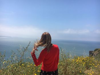 Rear view of woman standing by sea against sky