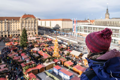 Rear view of woman in city against sky during winter