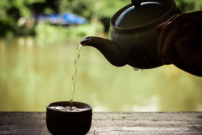 Close-up of hand pouring water in container