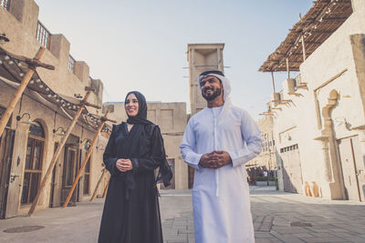 Low angle view of smiling couple talking while walking on street in town