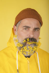 A handsome man with a brown cap and a flower beard on a yellow background