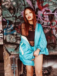 Portrait of smiling young woman against graffiti wall