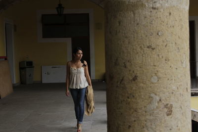 Full length of woman looking away while walking at corridor