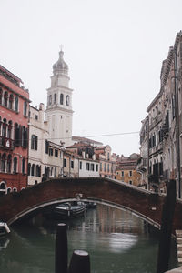 Bridge over canal amidst buildings against clear sky