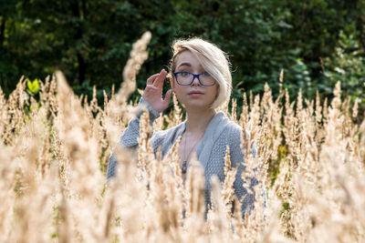Portrait of beautiful young woman wearing eyeglasses standing amidst plants