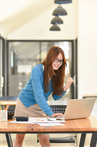 Young woman using mobile phone while sitting on table