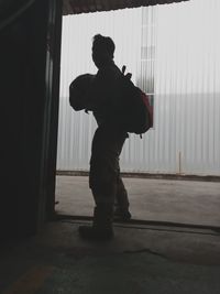 Rear view of man standing by window