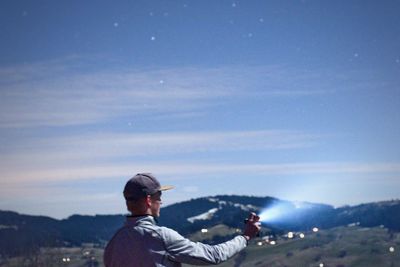 Man holding flashlight against sky