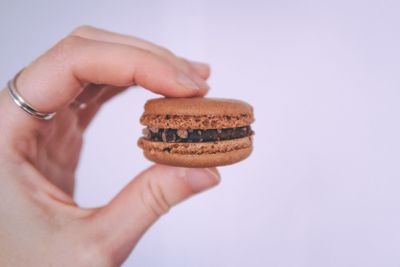 Close-up of hand holding ice cream over white background