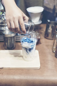 Close-up of hand pouring tea cup on table