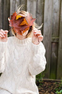 Midsection of woman holding maple leaves during autumn