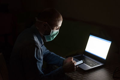 Side view of man using laptop at home