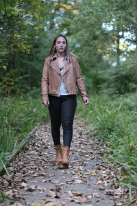 Portrait of young woman standing on footpath