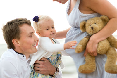 Baby girl with father and pregnant mother at beach