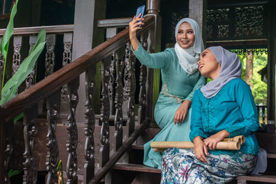 Full length of woman photographing with mobile phone standing outdoors