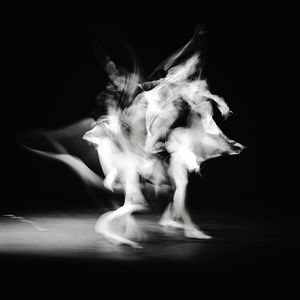 Blurred motion of man dancing against black background