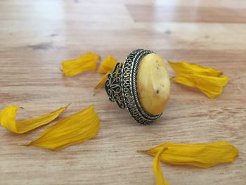 High angle view of yellow petals and ring on table