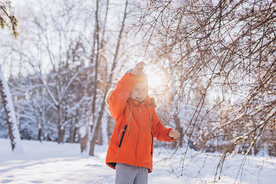 Little boy in winter snowy forest playing with snow. sunny winter day. frosty snowy winter.