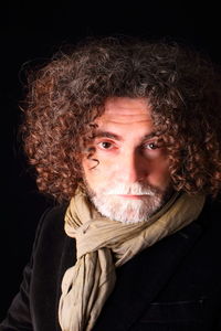 Close-up portrait of man with curly hair against black background