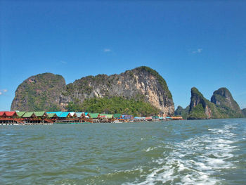 Scenic view of sea and rocks against clear blue sky