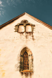 Low angle view of cross on building against sky