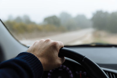 Close-up of person hand holding steering wheel