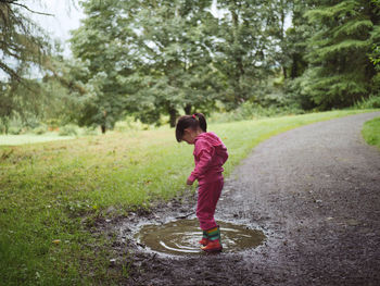 Full length of girl standing in puddle on road