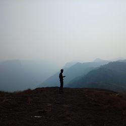 Silhouette man standing on mountain against sky