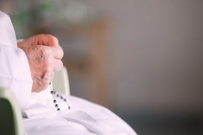 Midsection of man holding cross against blurred background